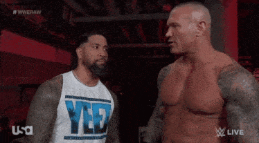 two wrestlers are standing next to each other and one of them is wearing a shirt that says yes
