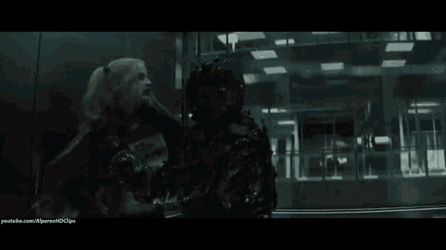 harley quinn from suicide squad is holding a gun in a dark room .