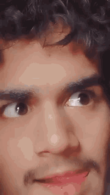 a man with curly hair and a mustache is making a funny face .