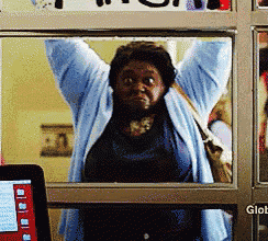 a woman in a blue sweater is standing in front of a glass door with the word glob on it