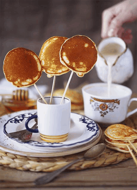 pancakes on sticks in a cup with milk being poured