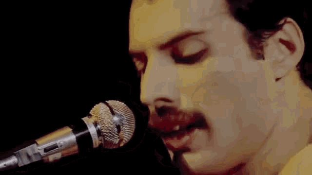 a man with a mustache is singing into a microphone .