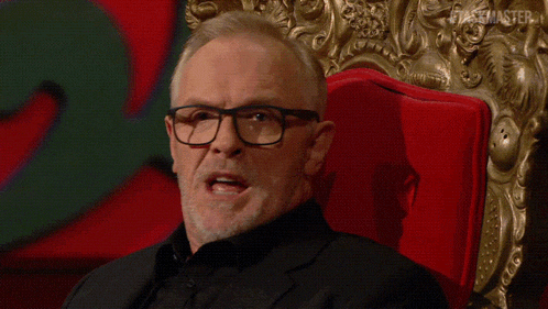 a man with glasses is sitting in a red chair with the words as if things weren 't sexy enough round here