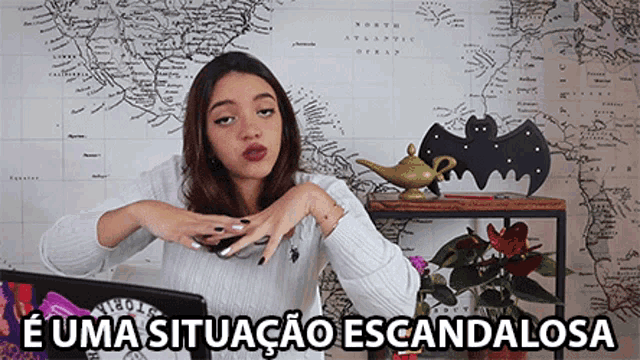 a woman sitting in front of a map with the words " e uma situacao escandalosa "