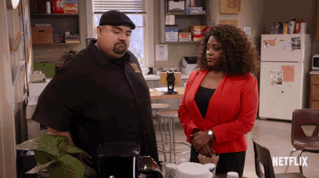 a woman in a red jacket is standing next to a man in a black shirt in a kitchen with a netflix logo visible