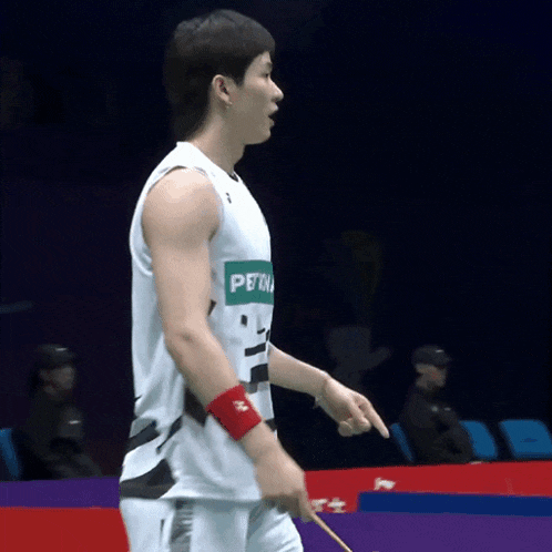 a man wearing a white tank top with petro on it shakes hands with another man