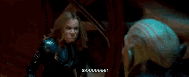a woman in a black jacket is screaming at a man in a room .