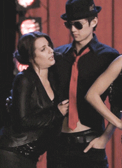 a man in a hat and red tie is standing next to a woman in a black jacket