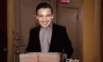a man in a suit is carrying a stack of pizza boxes .