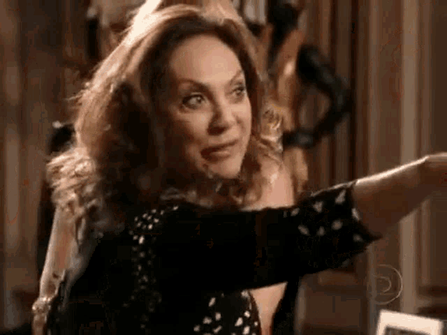 a woman in a black and white polka dot shirt is pointing her finger at something .