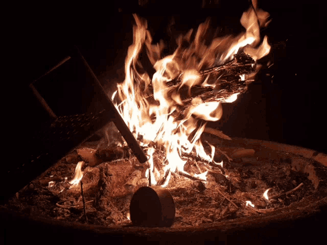 a fire is burning in a pit with a shovel in the foreground