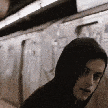 a man in a hooded sweatshirt is walking on a train