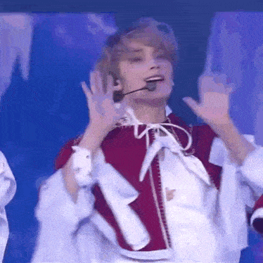 a young man in a red and white costume is dancing on a stage .