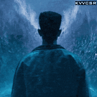 a man stands in front of a waterfall with a kvvcsr logo above him