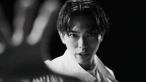 a black and white photo of a young man with his hand out