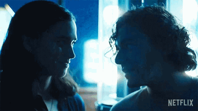 a man and a woman are looking at each other in a dark room with a netflix logo in the corner