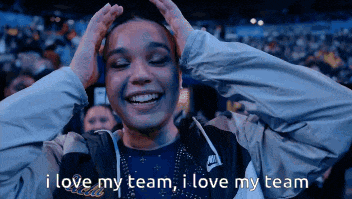 a woman in a nike jacket holds her hands to her head and says i love my team