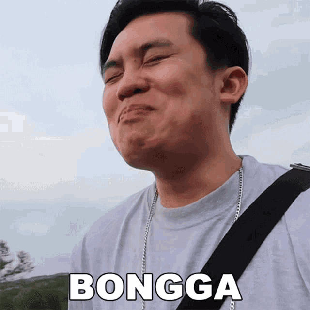 a man wearing a gray shirt and a black strap is making a funny face and the word bongga is above him
