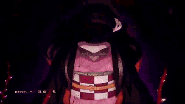a girl in a red dress is standing in a dark room surrounded by red flowers .