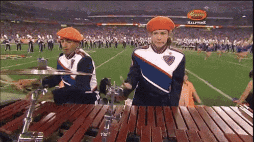 two marching band members are playing xylophones in front of a sign that says peanut butter halftime