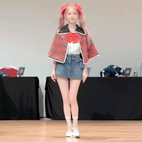 a girl wearing a plaid cape and a denim skirt