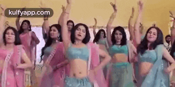 a group of women are dancing together in a room with their hands in the air .