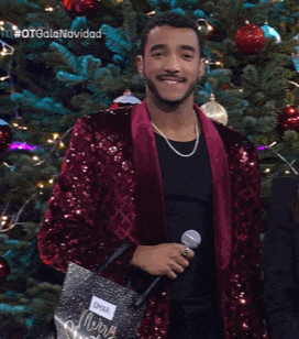 a man in a red sequined jacket is holding a bag that says merry christmas