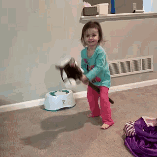 a little girl is playing with a stuffed animal in front of a potty that has the number 2 on it