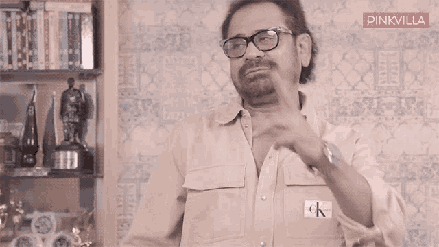 a man wearing glasses and a shirt with a ck logo on it
