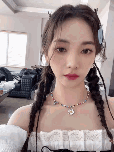 a woman with braids and a necklace with a flower pendant