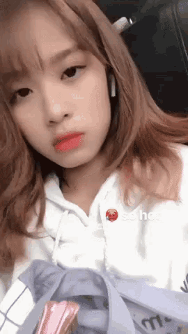 a girl wearing headphones and a white hoodie has a sticker on her face that says school