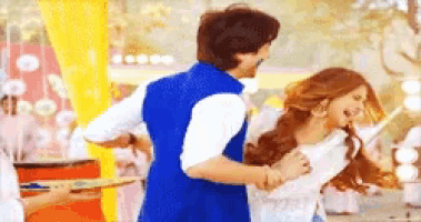 a man in a blue vest is holding a woman in his arms while they are dancing .