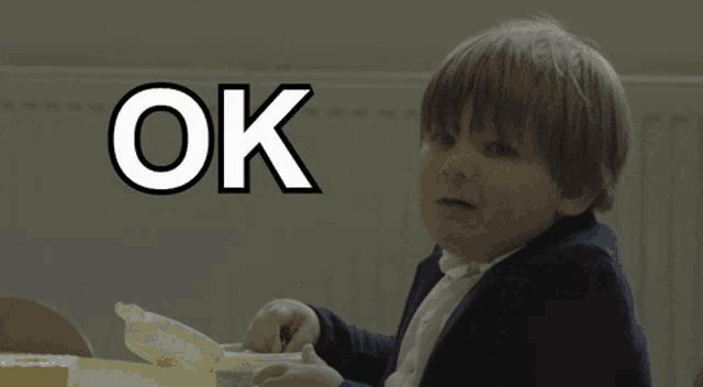 a young boy giving a thumbs up with the word ok behind him