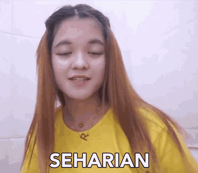 a woman wearing a yellow shirt has the word seharian on her chest