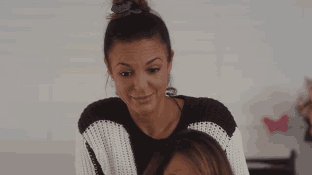 a woman in a black and white striped sweater looks at another woman