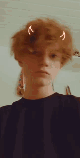 a young man with red hair has a devil horn on his head .