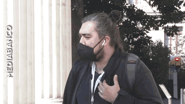 a man wearing a face mask is standing in front of a mediabanco sign