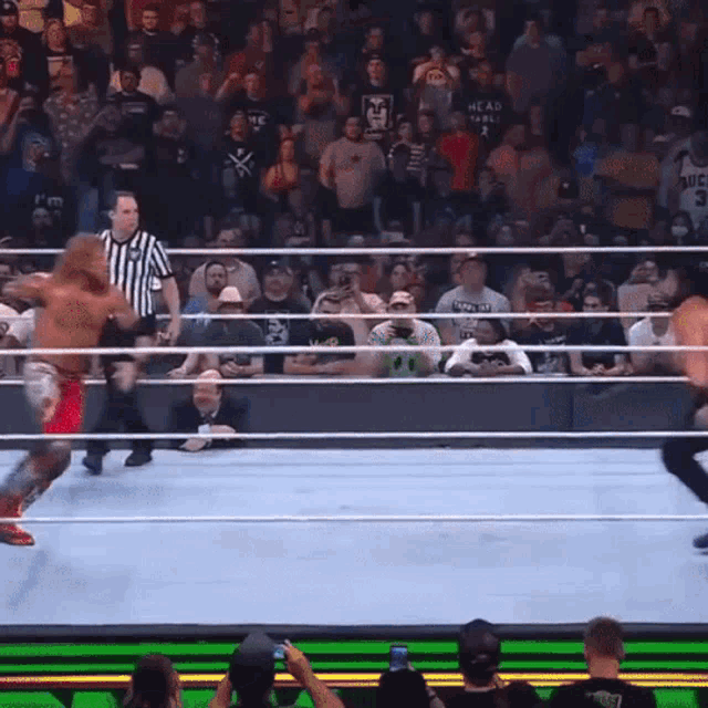 a wrestler wearing a shirt that says ' head to ball ' on it is in a wrestling ring