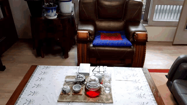 a chair sits in a living room next to a table with a tea set on it