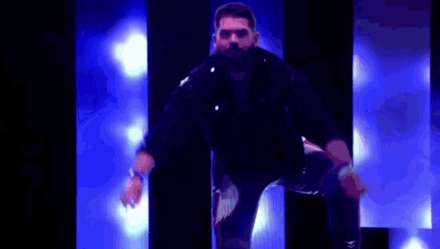 a man with a beard is dancing on a pole in front of a blue light .