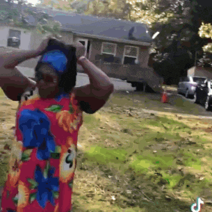 a woman wearing a floral dress is standing in front of a house