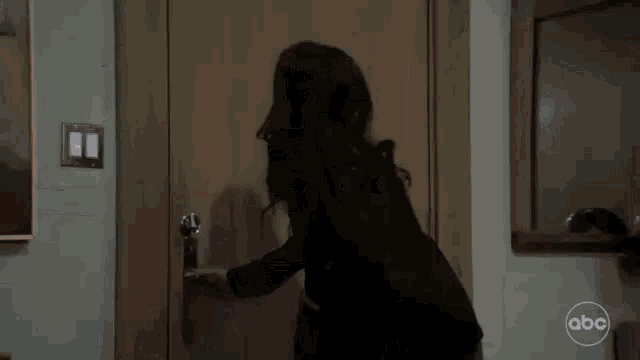 a woman is standing in front of a door and looking at the door .