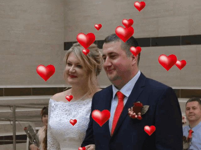 a man and a woman are standing next to each other with hearts flying around them
