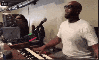 a man in a white shirt is playing a keyboard and singing into a microphone .