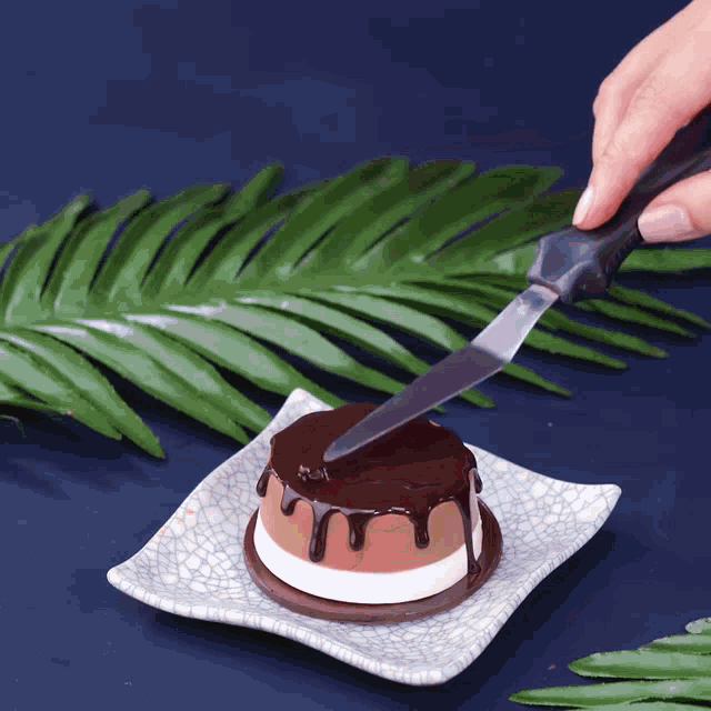 a person is cutting a dessert with a knife on a plate