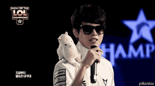 a man holding a stuffed animal in front of a sign that says lol champions