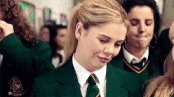 a girl in a green school uniform with a yellow collar and tie