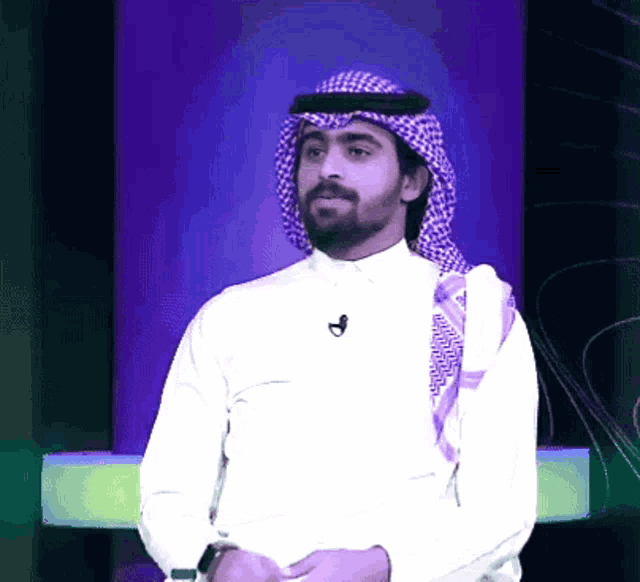 a man wearing a head scarf and a white shirt with a microphone on his neck