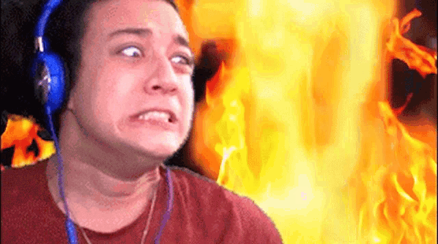 a man wearing headphones making a funny face in front of a fire .
