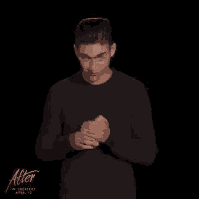 a young man in a black shirt is holding a cup of coffee and a candle .
